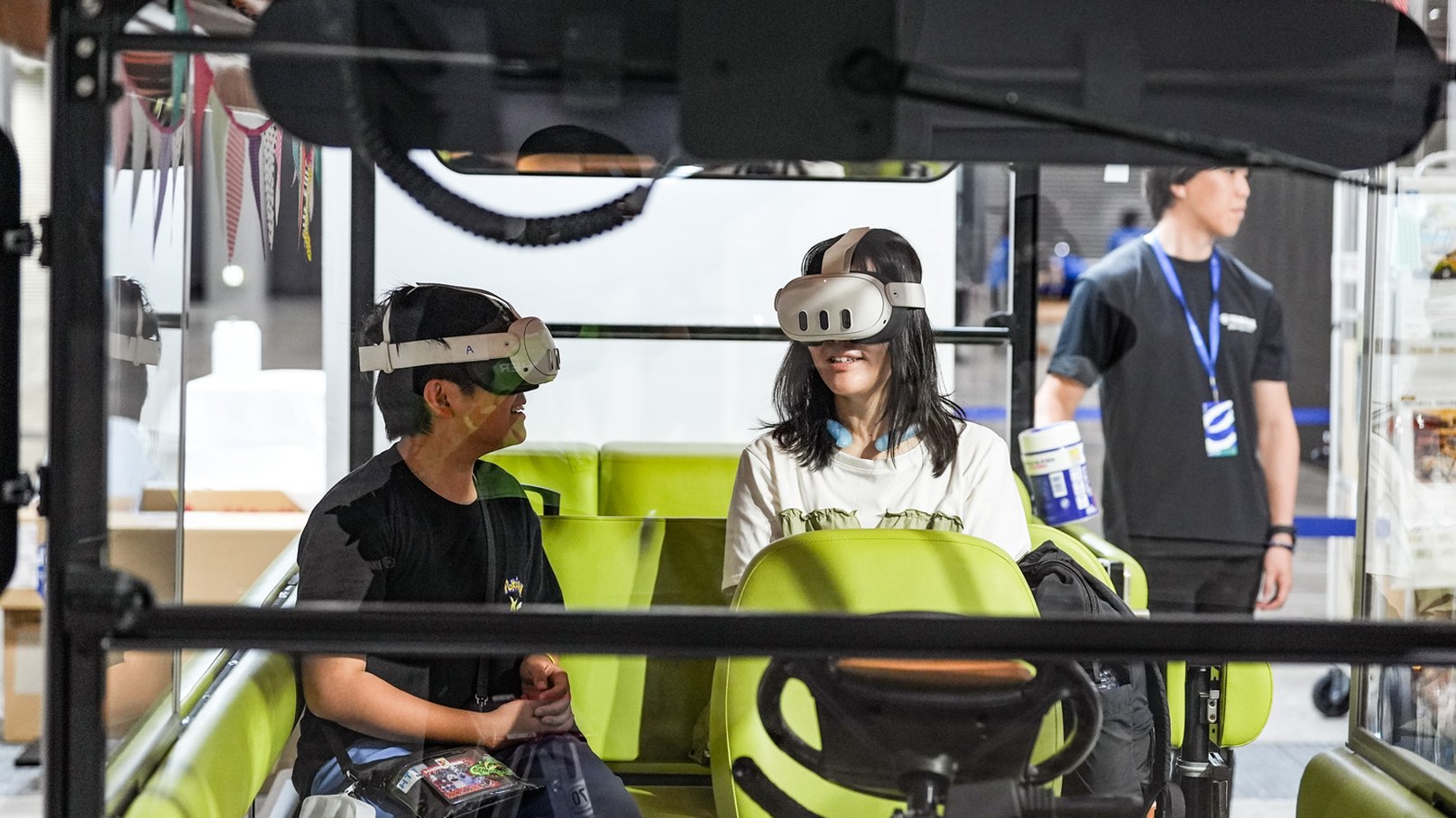 緑色のグリスロの座席でVRゴーグルを装着し、走行風景を体験する2名の来場者
