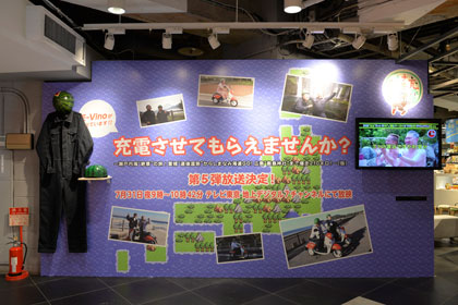 「E-Vino」で旅する『充電させてもらえませんか？』というテレビ東京の番組の紹介パネル。7月31日21時からオンエア、お見逃しなく。実際に出川さんが着用した衣装とヘルメットを展示しています