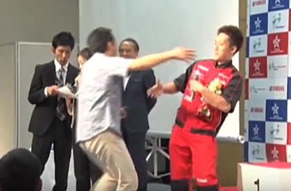 そして、優勝が決まった瞬間は「うれしすぎて抱きつきたかった」と抱きつきに行く金子社長（左）と、それをかわそうとする鮫島さん（右）