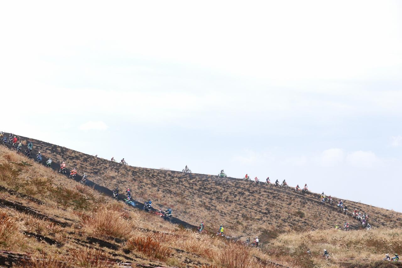 スコリアと呼ばれる、独特な質感を持つ火山灰の砂利が体積した山を登り、選手はこぶし大の火山岩がゴロゴロする溶岩っ原へ次々と突入してきます。